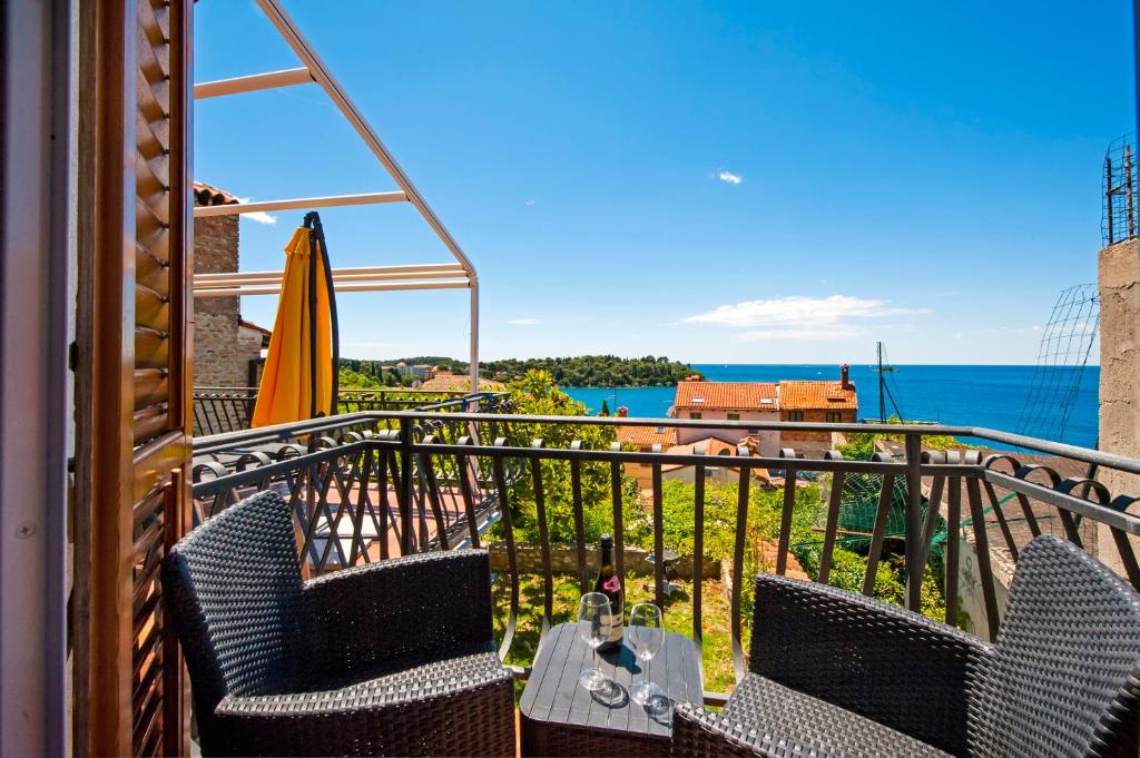 einen Balkon mit einem Tisch, einem Sonnenschirm und dem Meer in der Unterkunft Monte Holiday Home with Jacuzzi in Rovinj