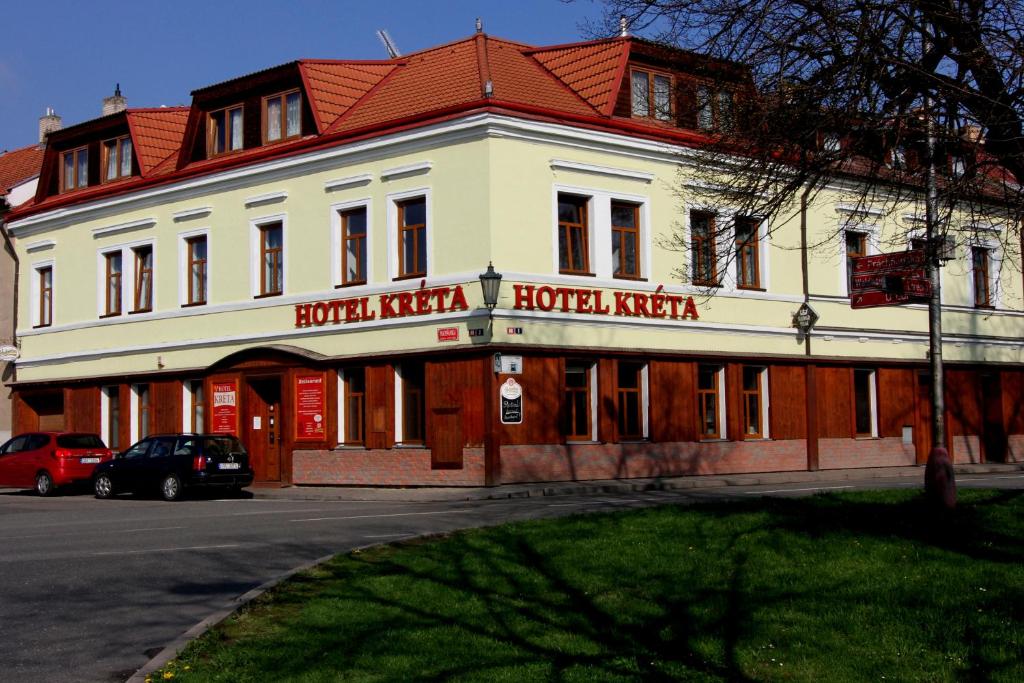 biały budynek z czerwonym dachem na ulicy w obiekcie Hotel Kreta w mieście Kutná Hora