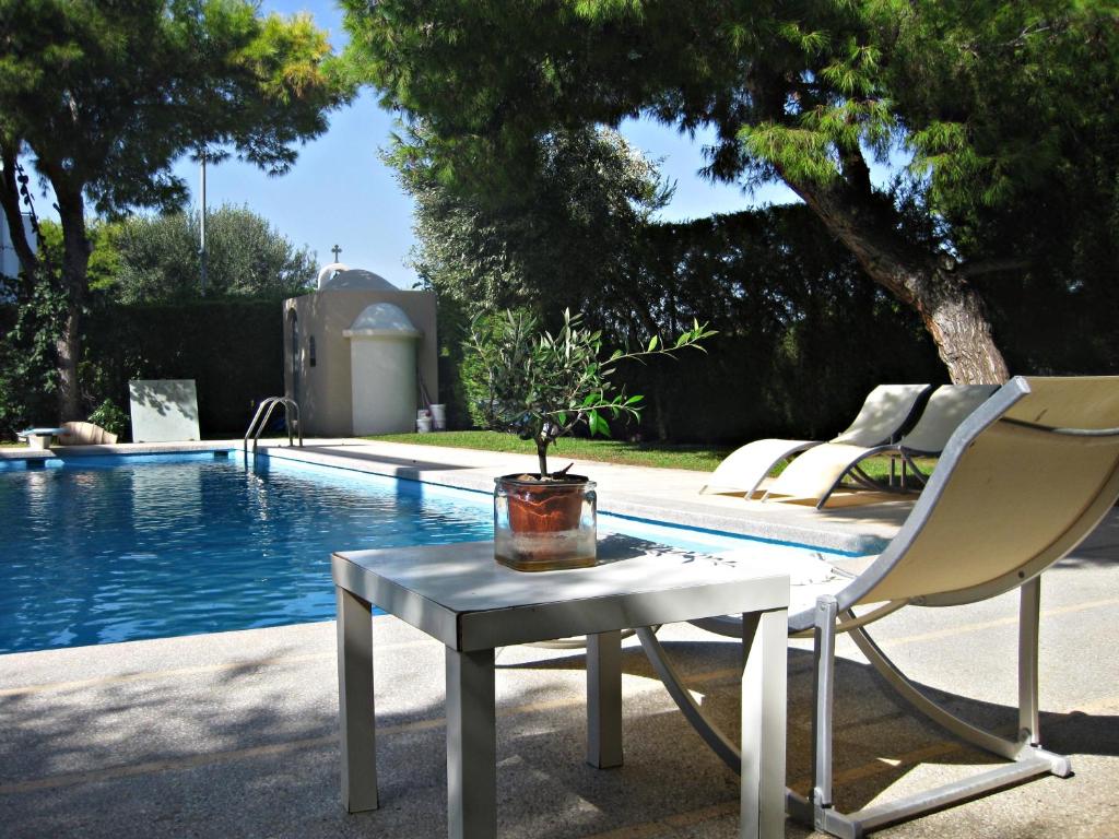 a table and a chair next to a pool at Villa Serenity in Porto Rafti