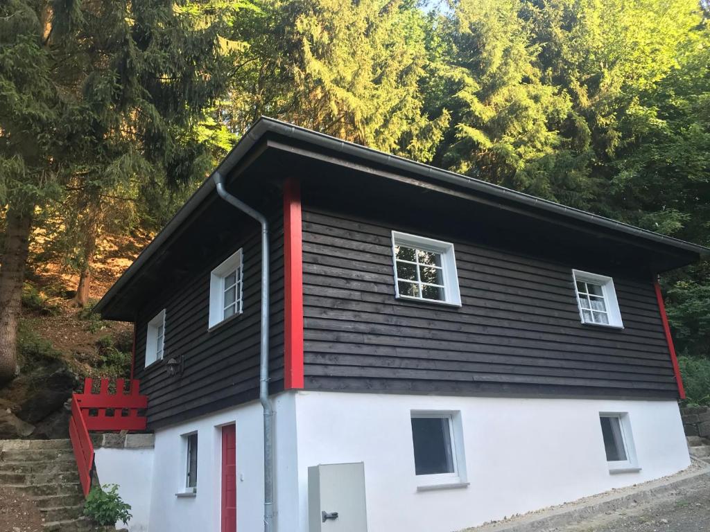 una pequeña casa con techo negro y adorno rojo en Blockhaus im Kuckuckswinkel, en Schöna