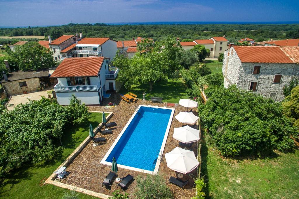 einen Luftblick auf einen Pool mit Sonnenschirmen und ein Haus in der Unterkunft Apartmani Halilovic in Umag