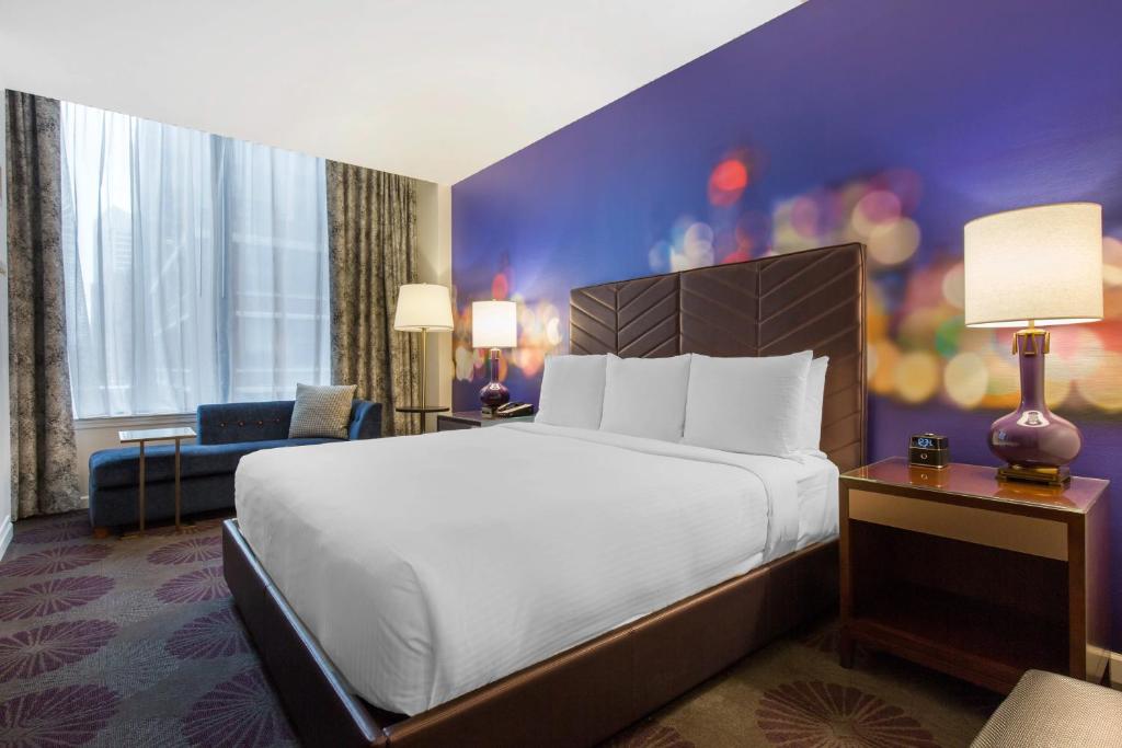 シカゴにあるThe Chicago Hotel Collection Magnificent Mileの大きなベッドと椅子が備わるホテルルームです。