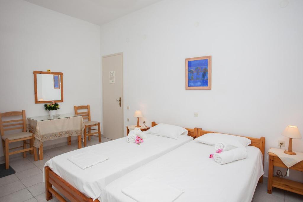 a bedroom with two beds and a table and chairs at Anestoula Rooms in Skala