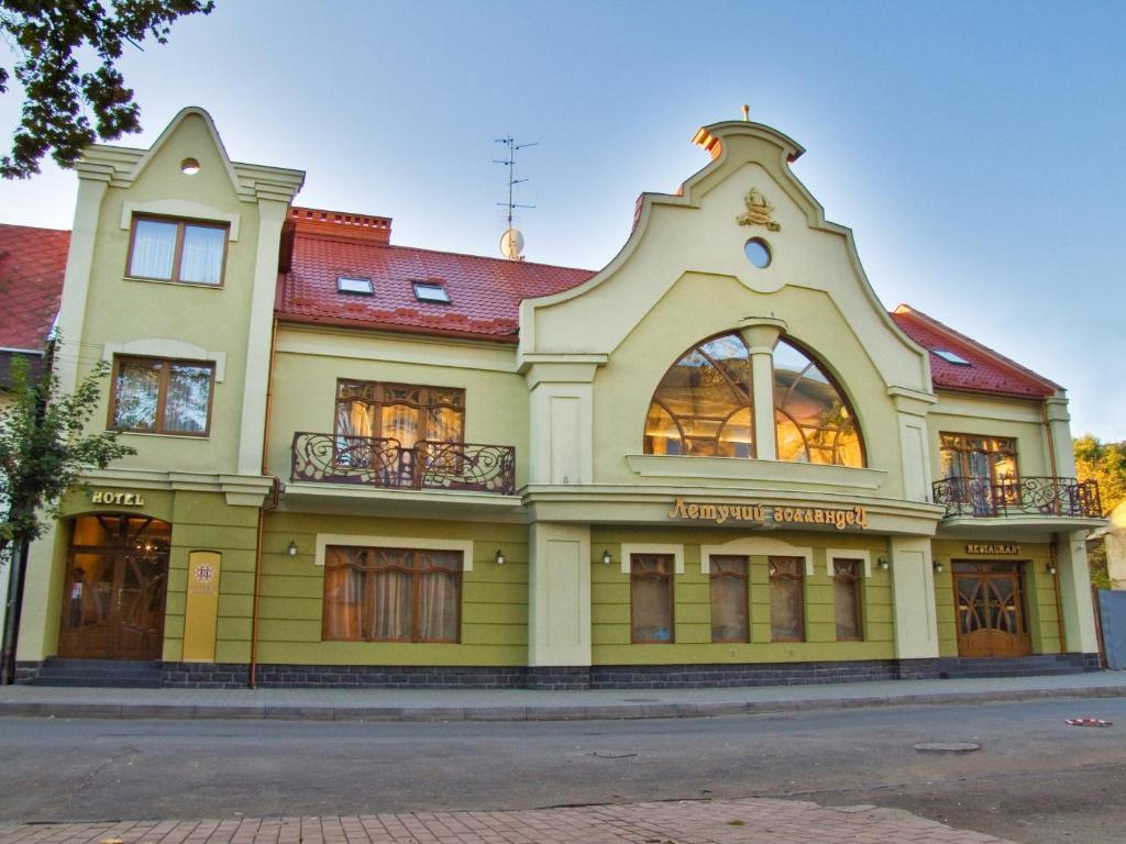 a yellow building with a red roof at Letuchiy Gollandets in Uzhhorod