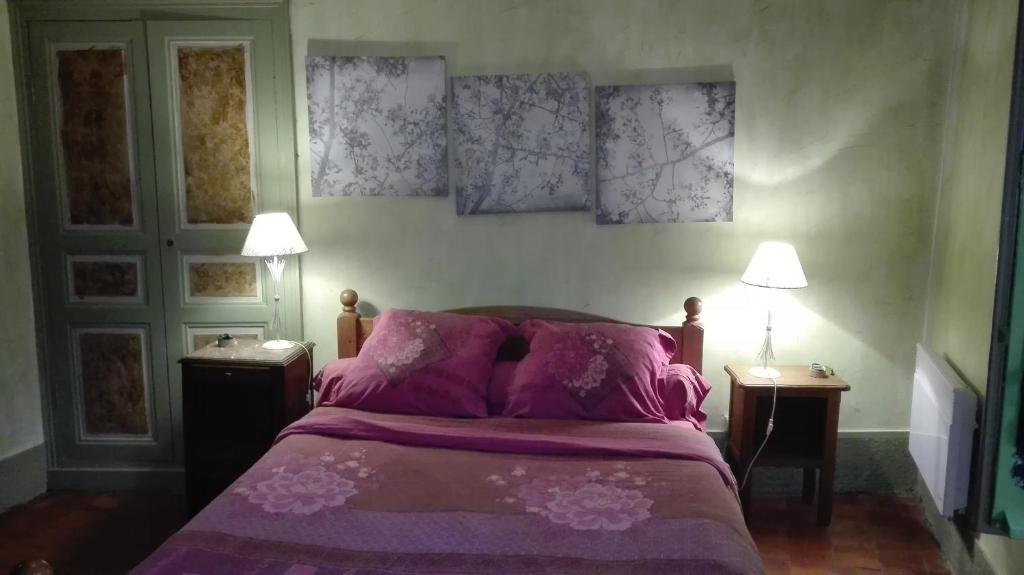 a bedroom with a bed with purple sheets and two lamps at Gite de charme au coeur de la Bourgogne in Santigny