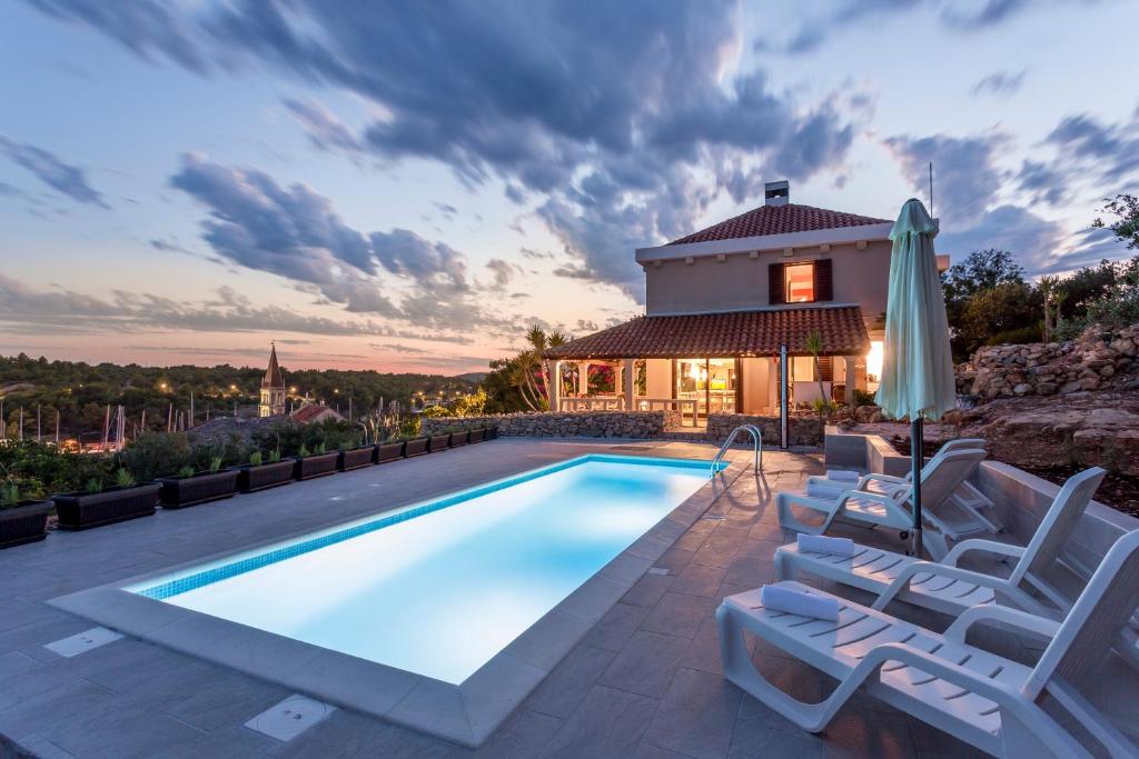 a swimming pool with chairs and a house at Villa Fortica in Milna