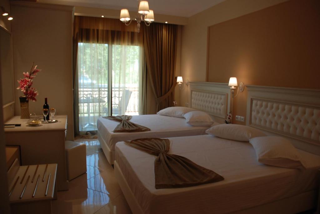 a hotel room with two beds and a window at Elxis Luxury Resort in Nea Vrasna