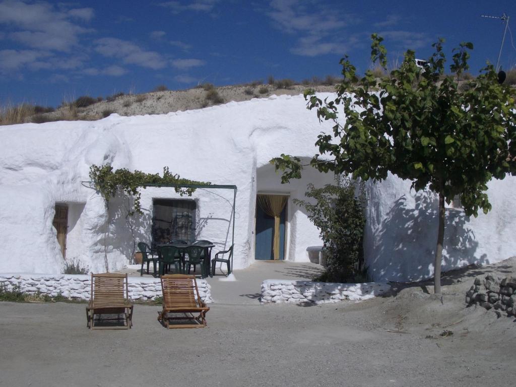 un edificio blanco con sillas y una mesa. en Cuevas Alcobas en Baza