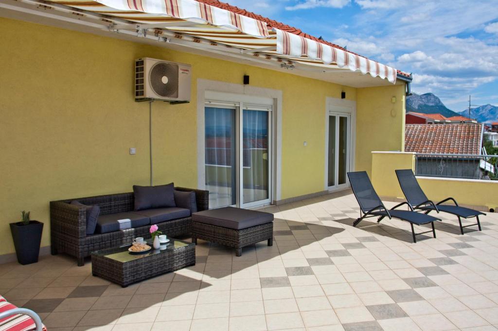 a patio with a couch and chairs on a roof at Apartment Noel in Kaštela
