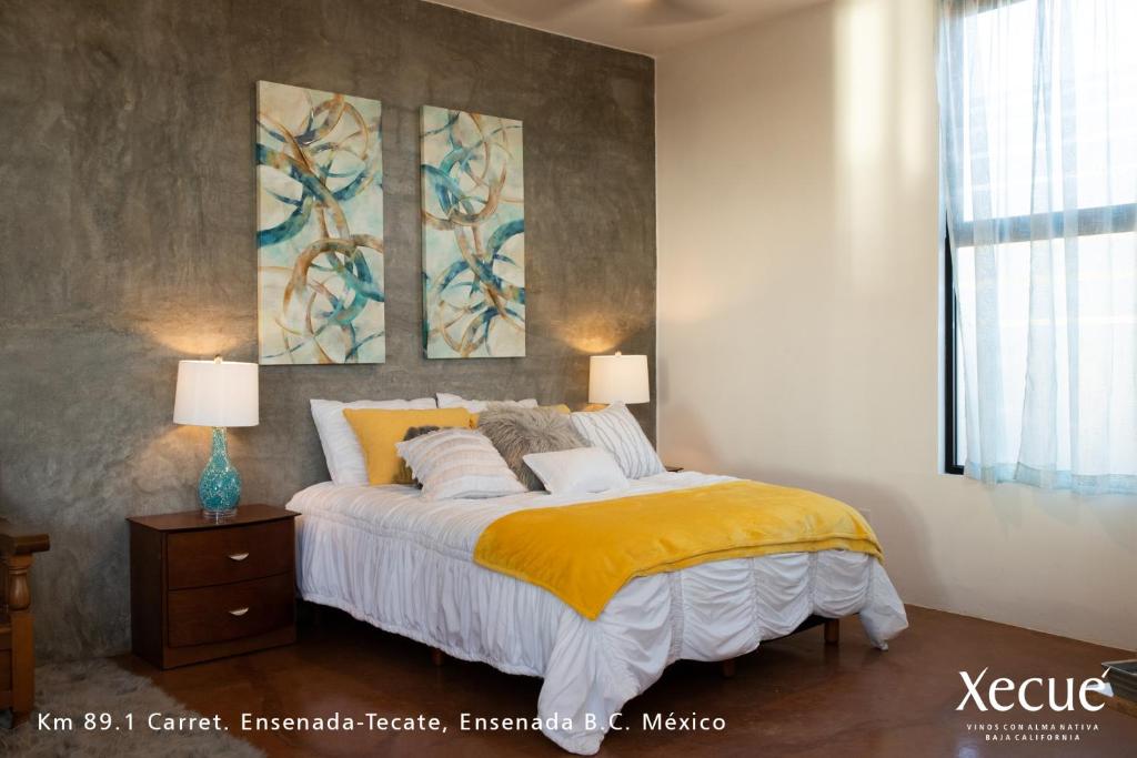 a bedroom with a bed and two paintings on the wall at Vinos Xecué in Ensenada