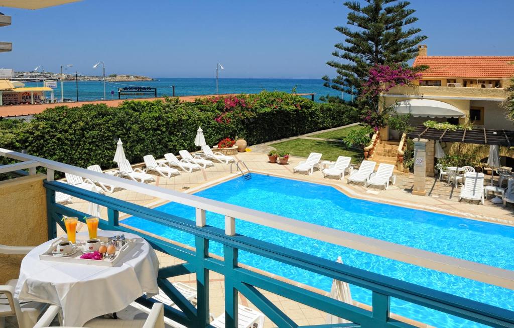 einen Pool mit Stühlen und einem Tisch auf dem Balkon in der Unterkunft Petra Beach Hotel in Hersonissos