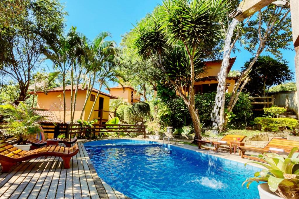a swimming pool in a yard with chairs and trees at Pousada Happiness - Ferradura in Búzios