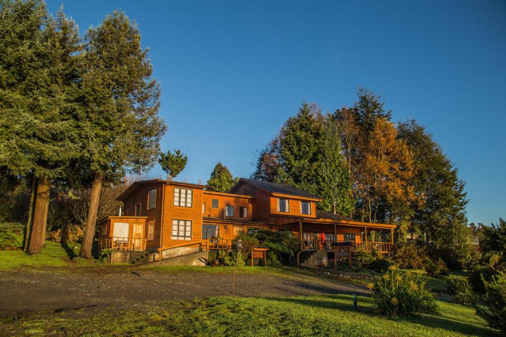 ein großes Haus auf einem Hügel mit Bäumen in der Unterkunft Apart hotel Puchaley Lafquen in Panguipulli