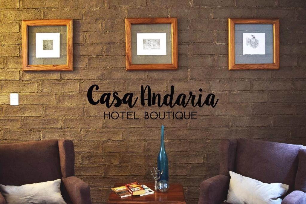 San José Iturbide的住宿－Hotel Casa Andaria，砖墙上的标志,上面有两把椅子和一张桌子