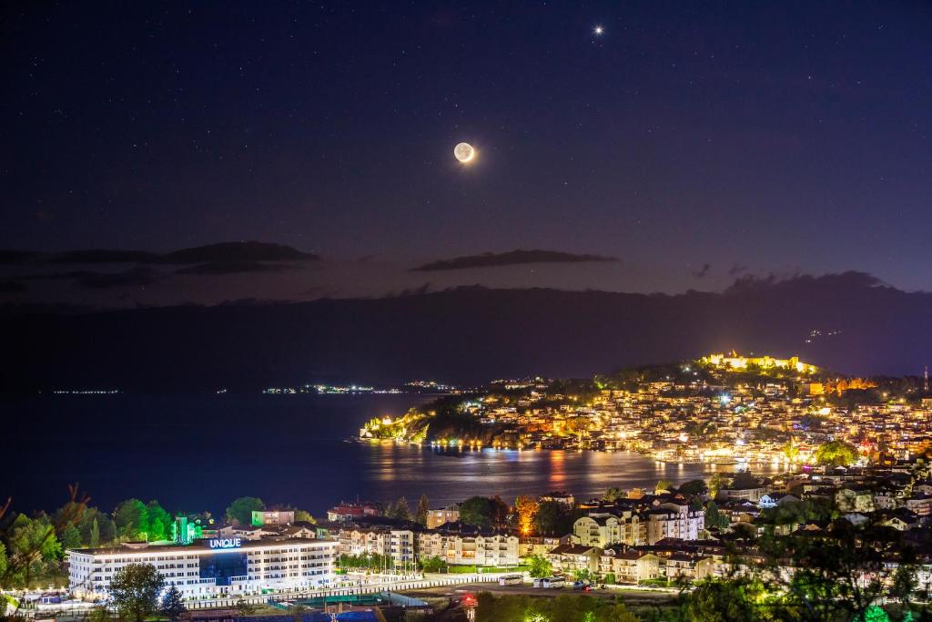 a view of a city at night with the moon at Unique - Resort and SPA in Ohrid