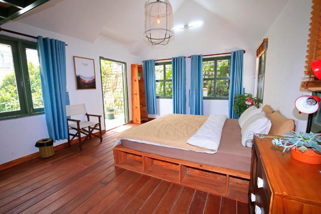 a bedroom with a large bed with blue curtains at Six Six Garden in Da Lat