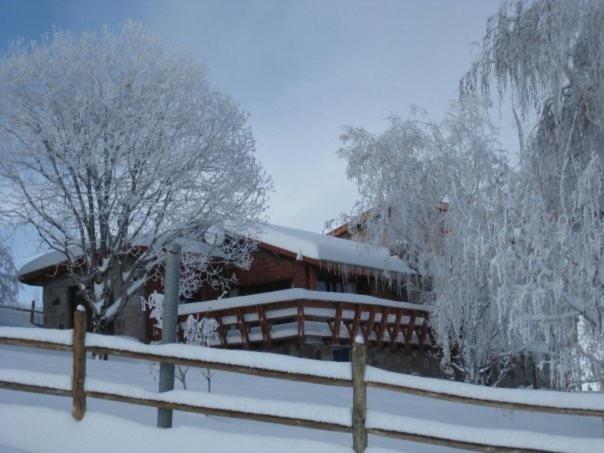 una casa cubierta de nieve junto a una valla en Loma del Viento, en Farellones