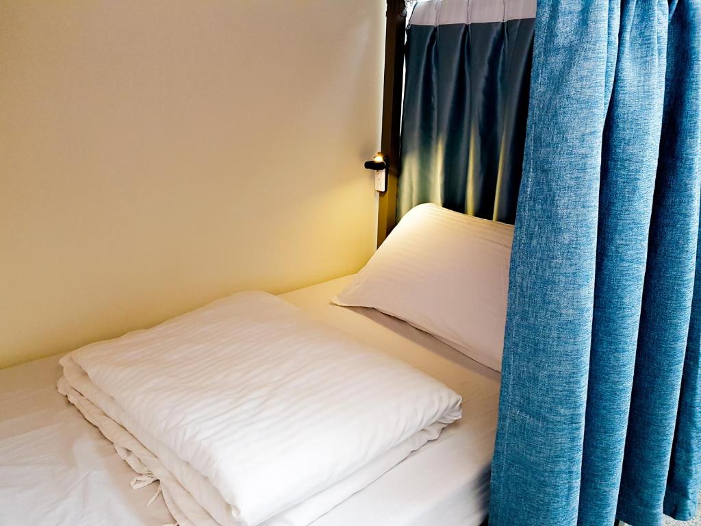 a bed with a pillow and a blue curtain at Gather in Tainan
