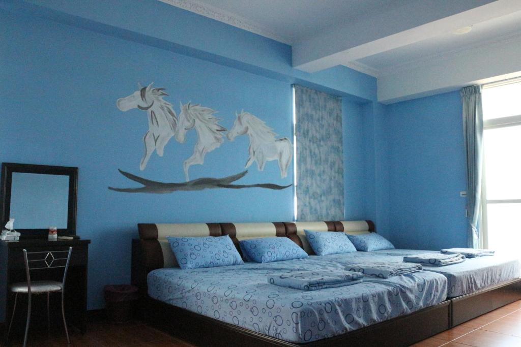 um quarto azul com uma cama com cavalos na parede em 驫風民宿 Equuleus Homestay em Magong