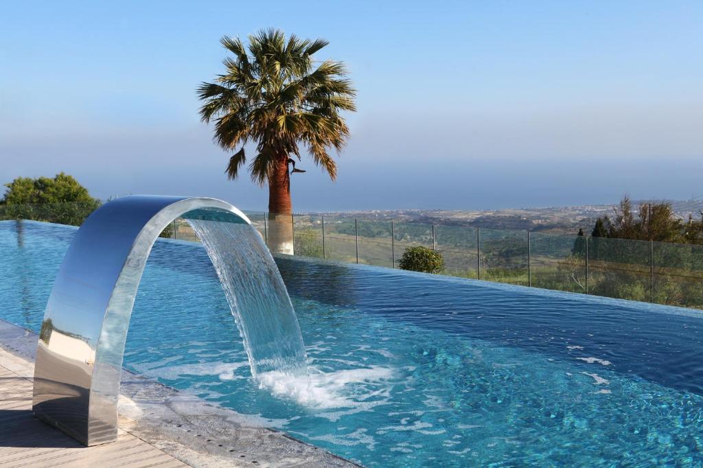 una piscina con una fuente frente a una palmera en Droushia Heights Hotel en Droushia