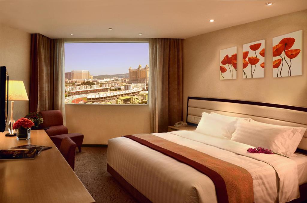 a hotel room with a bed and a large window at Grandview Hotel Macau in Macau