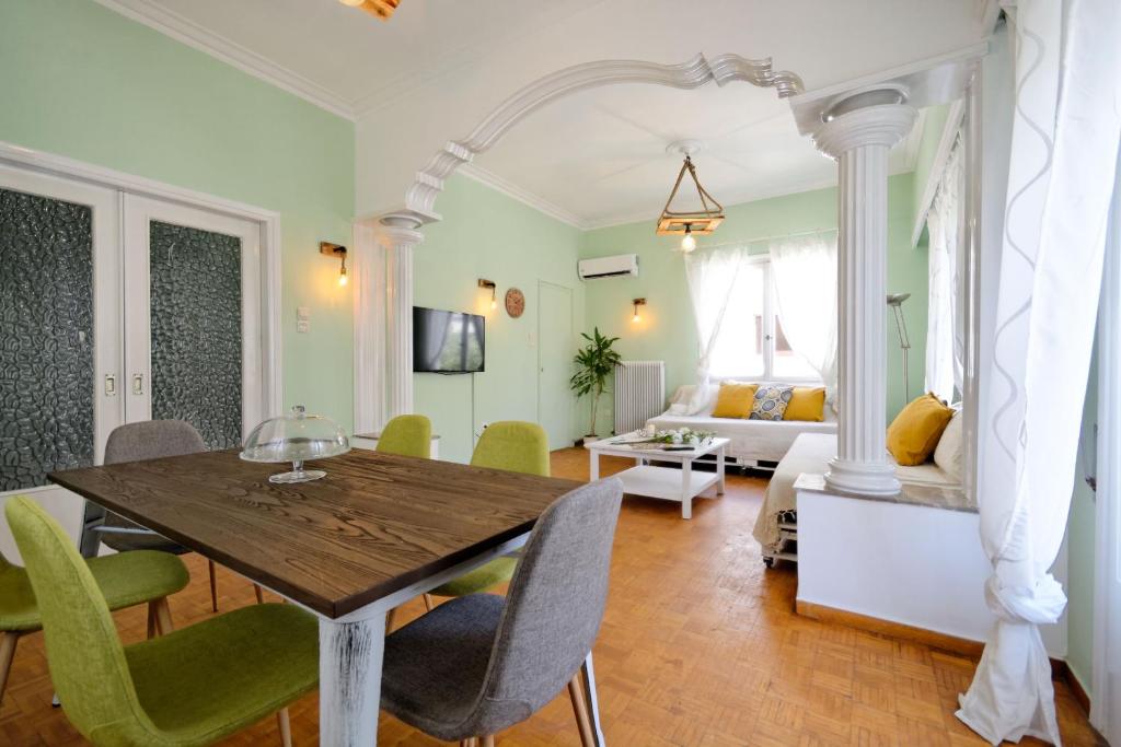 ein Wohnzimmer mit einem Holztisch und grünen Stühlen in der Unterkunft Kosta's Cottage House in Athen