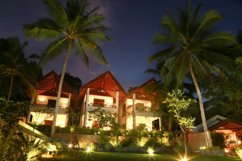 a resort with palm trees and lights at night at Goyambokka Guesthouse in Tangalle
