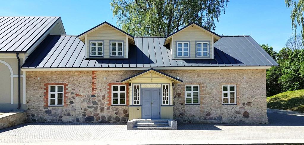 a large brick house with a metal roof at Pajusi Mõisa Külalistemaja in Põltsamaa