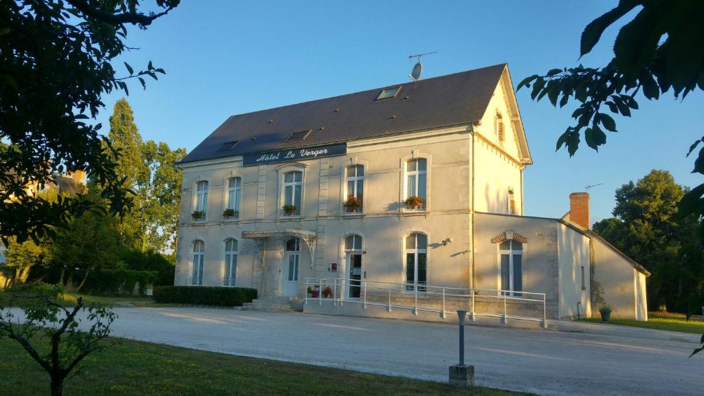 un grand bâtiment blanc avec un toit dans l'établissement Hôtel Le Verger, à Saint-Laurent-Nouan