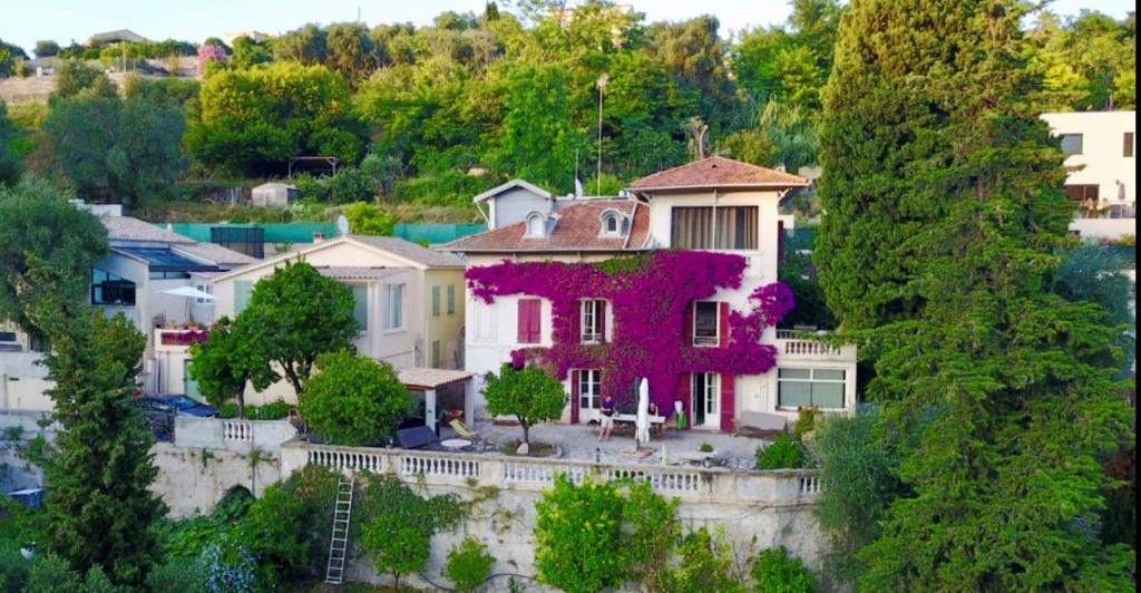 une maison avec des fleurs violettes sur son côté dans l'établissement Castel Enchanté, à Nice