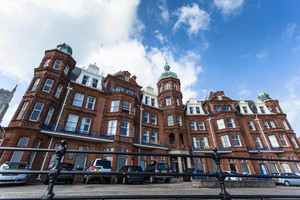 a large brick building with cars parked in front of it at Hotel De Paris in Cromer