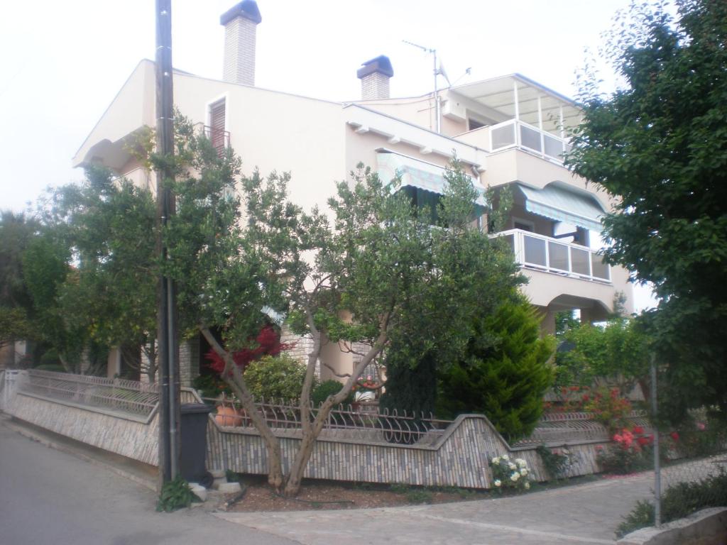 a white building with trees in front of it at Apartments & Room Diana in Pakoštane