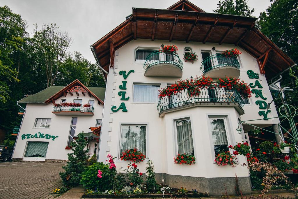 um edifício branco com caixas de flores em Szandy em Sovata