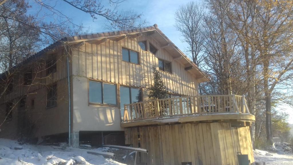 a house with a wrap around deck in the snow at le relais des fees in Saint-Martin-de-Caralp