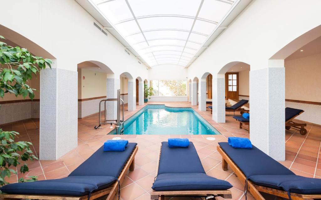 a pool in a building with blue chaise lounges at Hotel Cala Fornells in Paguera