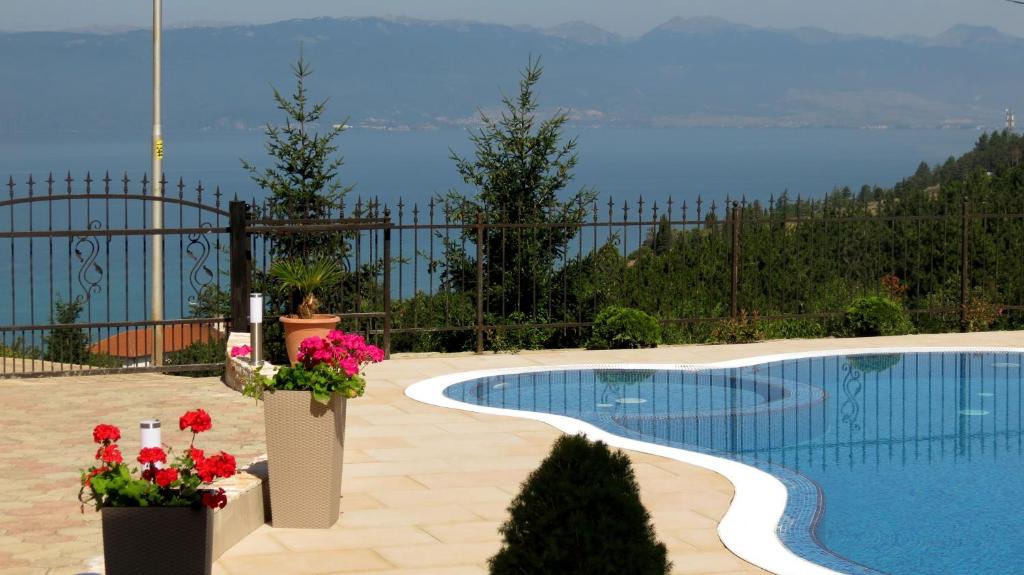 a swimming pool with flowers and a view of the water at Villa Angelos in Ohrid