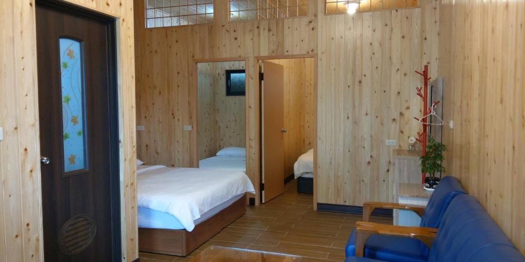 a bedroom with wooden walls and a bed and a couch at Zhong Ming Ju Taoyi Fang in Fanlu