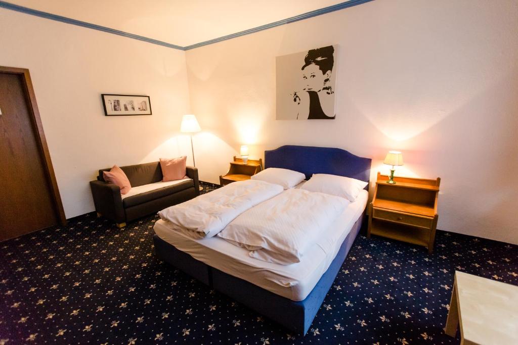 um quarto de hotel com uma cama e um sofá em Hotel Fabritz em Essen