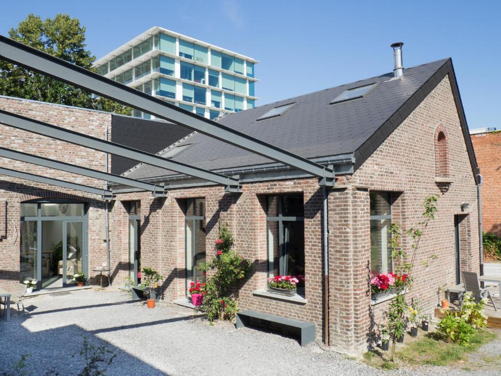 een bakstenen huis met een gebouw op de achtergrond bij Au jardin des Vennes in Luik
