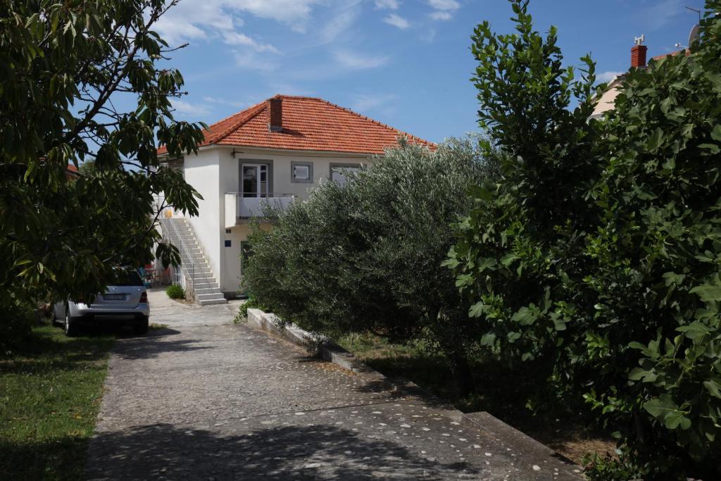 ein weißes Haus mit rotem Dach und einigen Büschen in der Unterkunft Apartment Vodice in Vodice