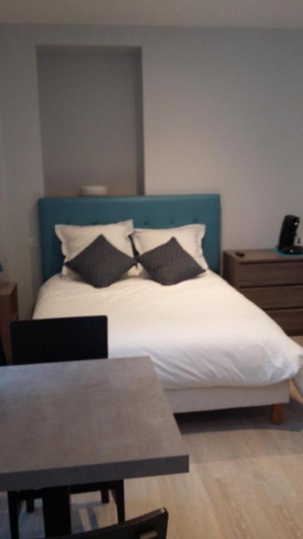 sypialnia z łóżkiem z niebieskim zagłówkiem i poduszkami w obiekcie Le Logis d'Isabelle w mieście Argentan