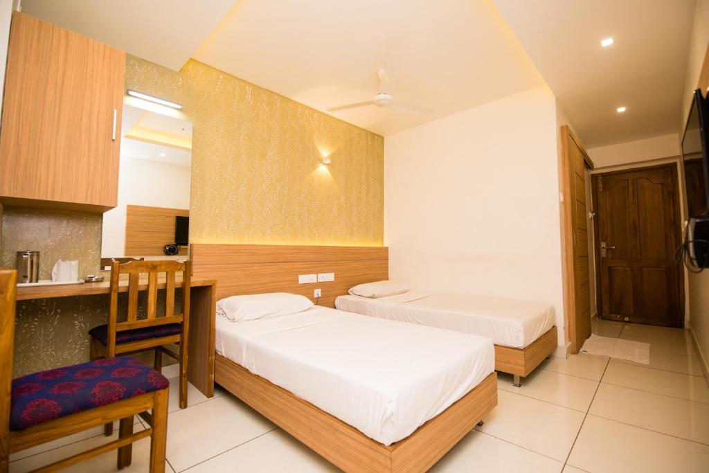 a small bedroom with two beds and a kitchen at Hotel Kapilavasthu in Palakkad