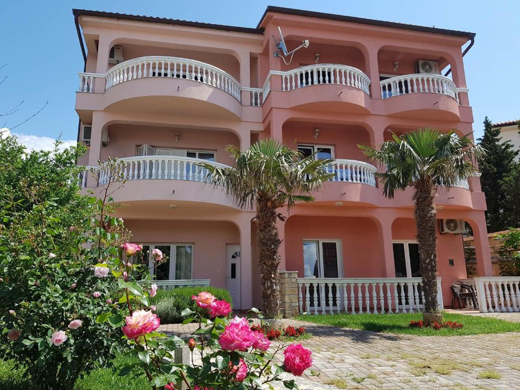 a pink house with palm trees in front of it at Apartments Ban in Novi Vinodolski