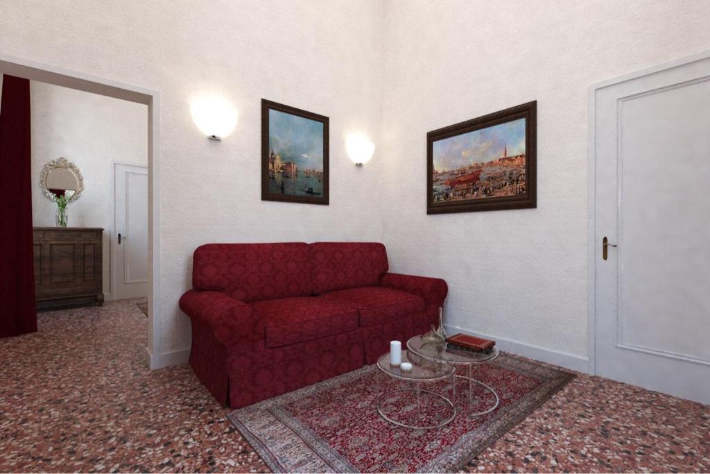 un soggiorno con divano rosso e tavolo di Suites alla Maddalena a Venezia