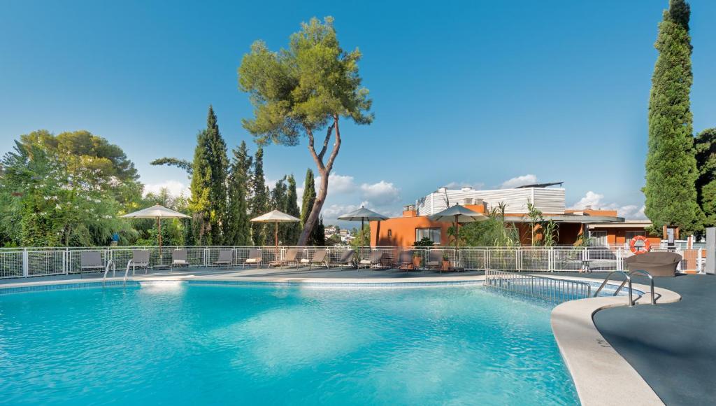 ein großer Pool mit Bäumen und ein Gebäude in der Unterkunft Hesperia Ciudad de Mallorca in Palma de Mallorca