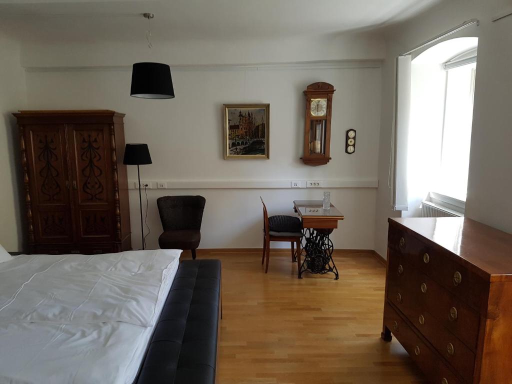 SIPPO Apartments في ليوبليانا: غرفة نوم بسرير ومكتب وساعة