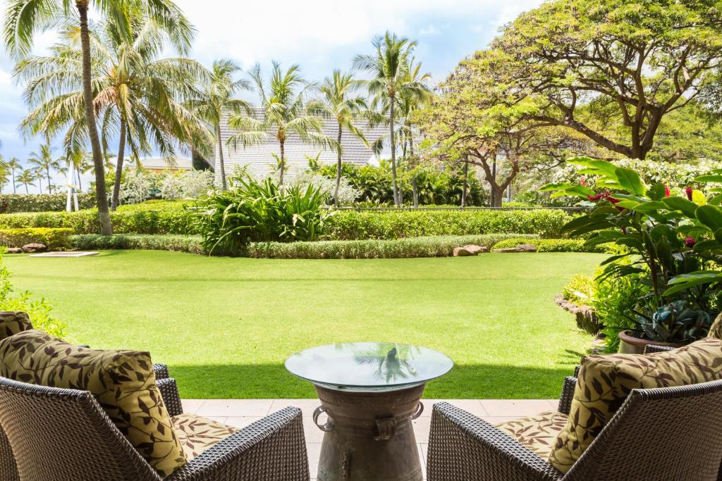 a patio with chairs and a table and a lawn at Popular Ground Floor with Extra Grassy Area - Beach Tower at Ko Olina Beach Villas Resort in Kapolei