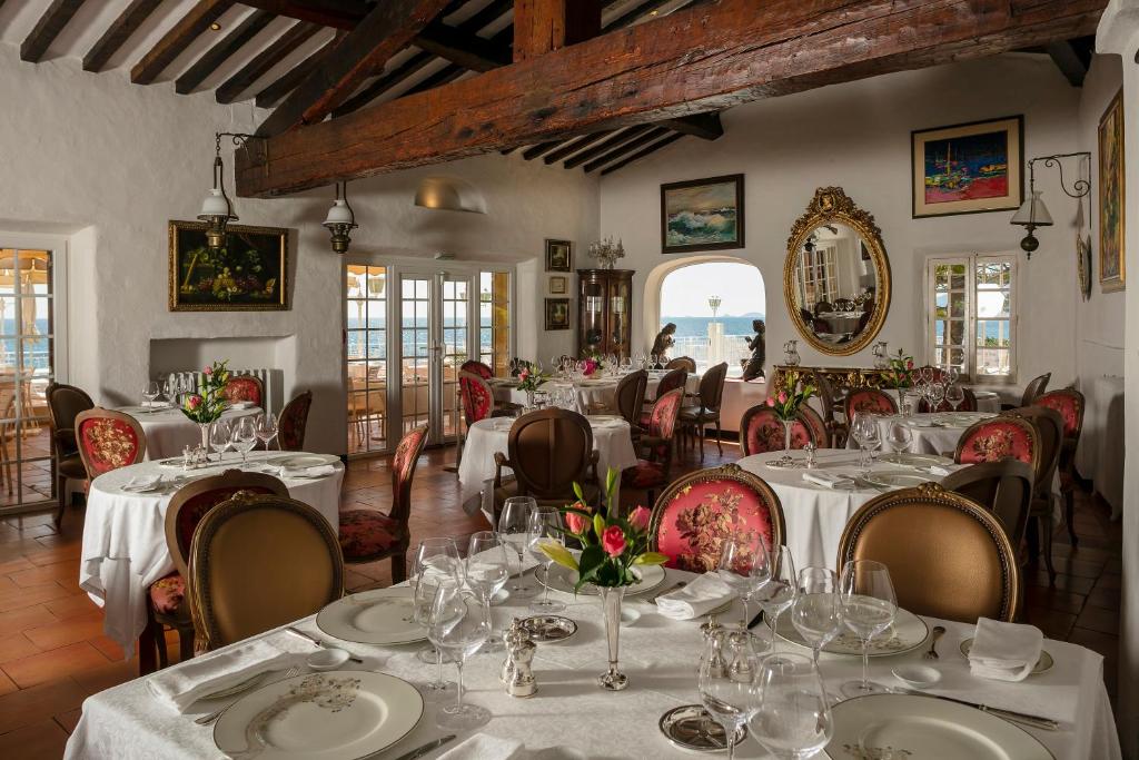 a restaurant with tables and chairs with white tablecloths at Hotel Le Maquis in Porticcio