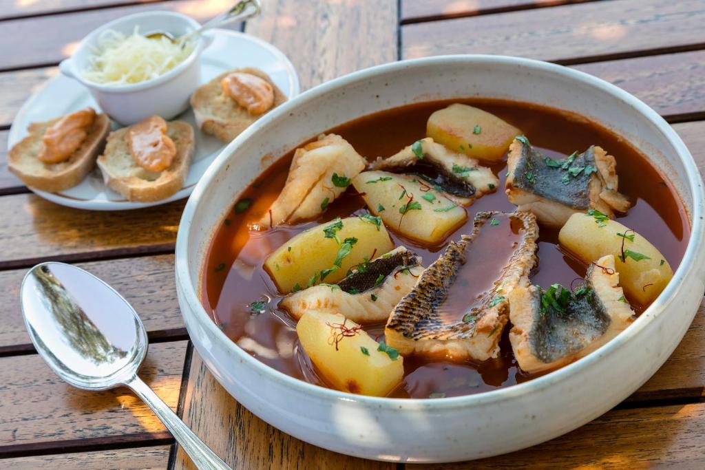 a bowl of soup with meat and potatoes on a table at Hotel Le Maquis in Porticcio