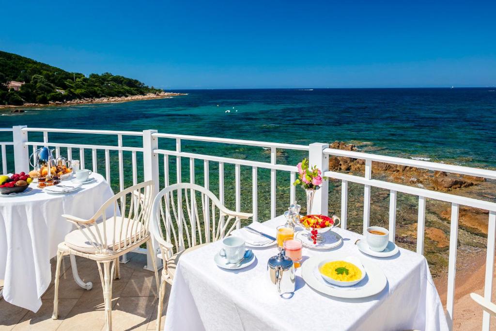 a table with plates of food on a balcony overlooking the ocean at Hotel Le Maquis in Porticcio